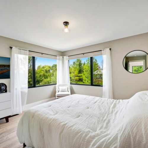 Bedroom #3 with ensuite and features large windows that offer stunning views of the wooded property.
