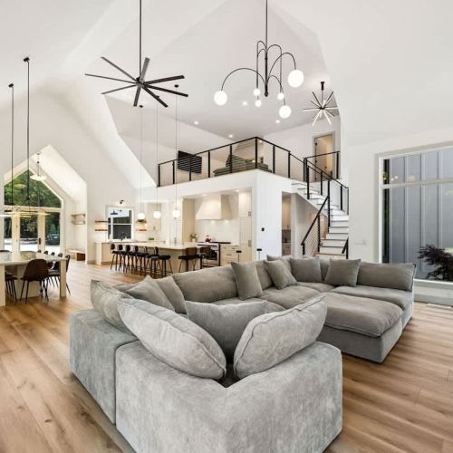 The open-concept living and dining areas boast soaring ceilings, large windows, and clean Scandinavian lines, creating a warm, light-filled space ideal for gathering