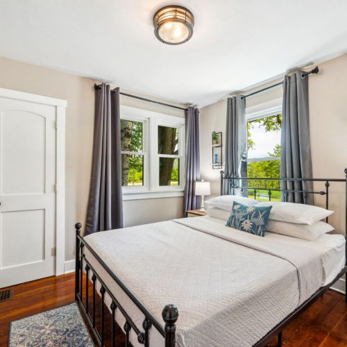 Relax in the tranquil main-level bedroom, featuring a comfortable queen-sized bed and elegant decor. Large windows provide plenty of natural light and scenic views.