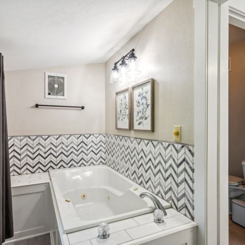 Indulge in the luxurious upper-level main bedroom bathroom, featuring a relaxing jetted tub and modern vanity. The stylish design and ample natural light create a spa-like retreat.