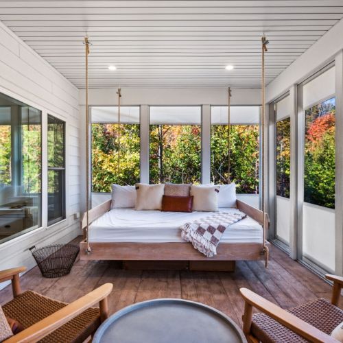 This porch is a standout feature, offering a cozy swing bed, TV, and seating area where you can enjoy meals, morning coffee, or quiet evenings surrounded by nature.