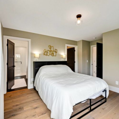 Bedroom #3 with ensuite and features large windows that offer stunning views of the wooded property.