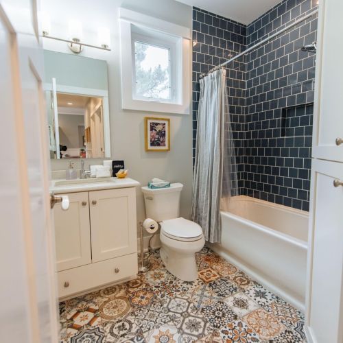 This beautifully appointed full bathroom features a stunning dark-tiled tub and shower combo, adding a touch of modern elegance.