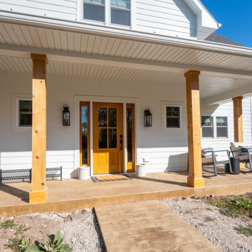 The wrap-around front porch provides additional outdoor living space, perfect for lounging and taking in the wooded surroundings.