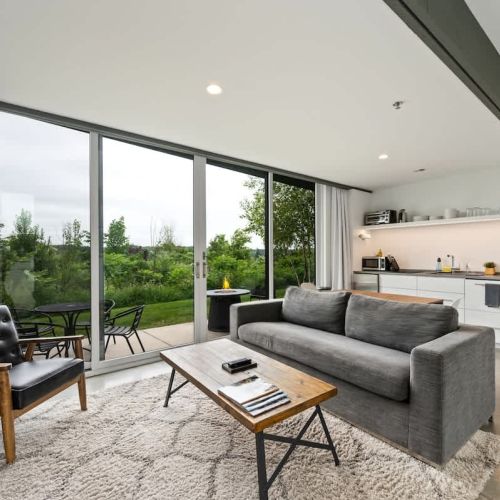 Enjoy open-concept living with sleek finishes, a cozy lounge space, and wall-to-wall views of nature.