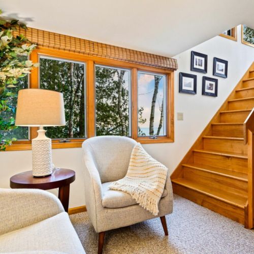 This cozy corner, with its comfortable chairs and soft throw blanket, is bathed in natural light from the windows overlooking the lake, offering a serene spot to enjoy a morning coffee or to lose yourself in a good book.