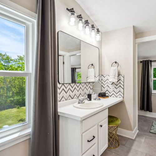 Indulge in the luxurious upper-level main bedroom bathroom, featuring a relaxing jetted tub and modern vanity. The stylish design and ample natural light create a spa-like retreat.