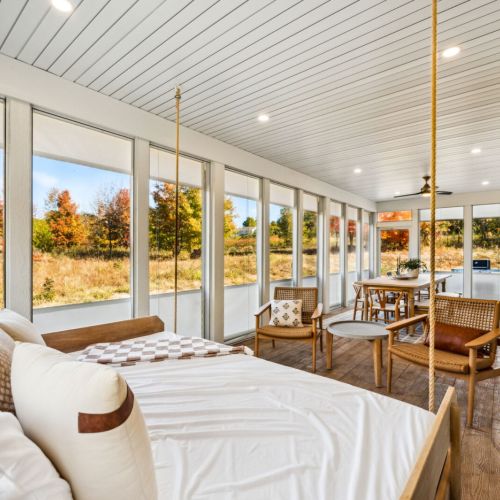 The screened-in porch is a standout feature, offering a cozy swing bed, TV, and seating area where you can enjoy meals, morning coffee, or quiet evenings surrounded by nature.