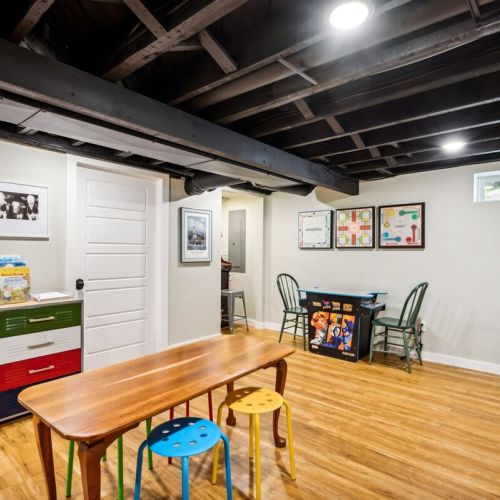 The full basement is a recreation space with two video game consoles, toys, bumper pool, a 65" Roku tv, and comfortable seating.