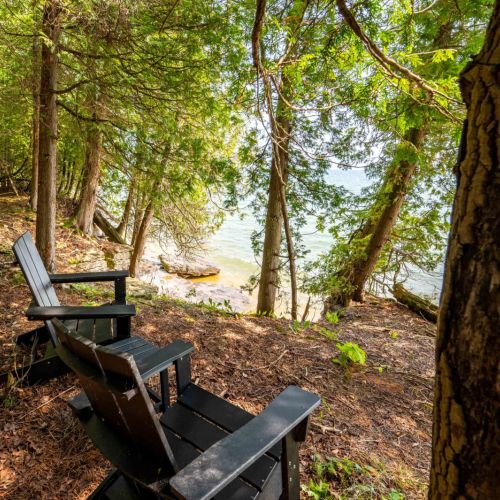 Rest and relax by the shoreline, listening to the soothing sound of waves while lounging in the hammock or settling into the cozy Adirondack chairs.